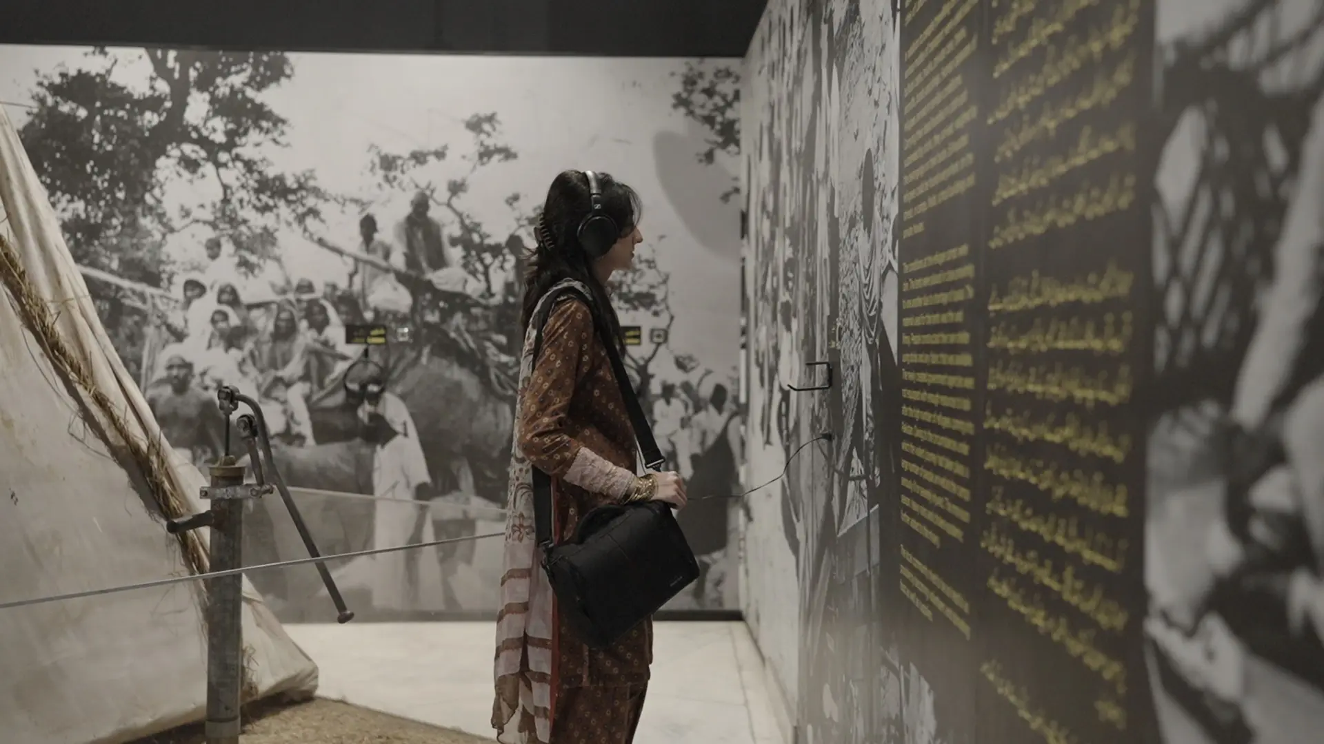 A participant with headphones listens to an oral history recording beside photographs of Partition